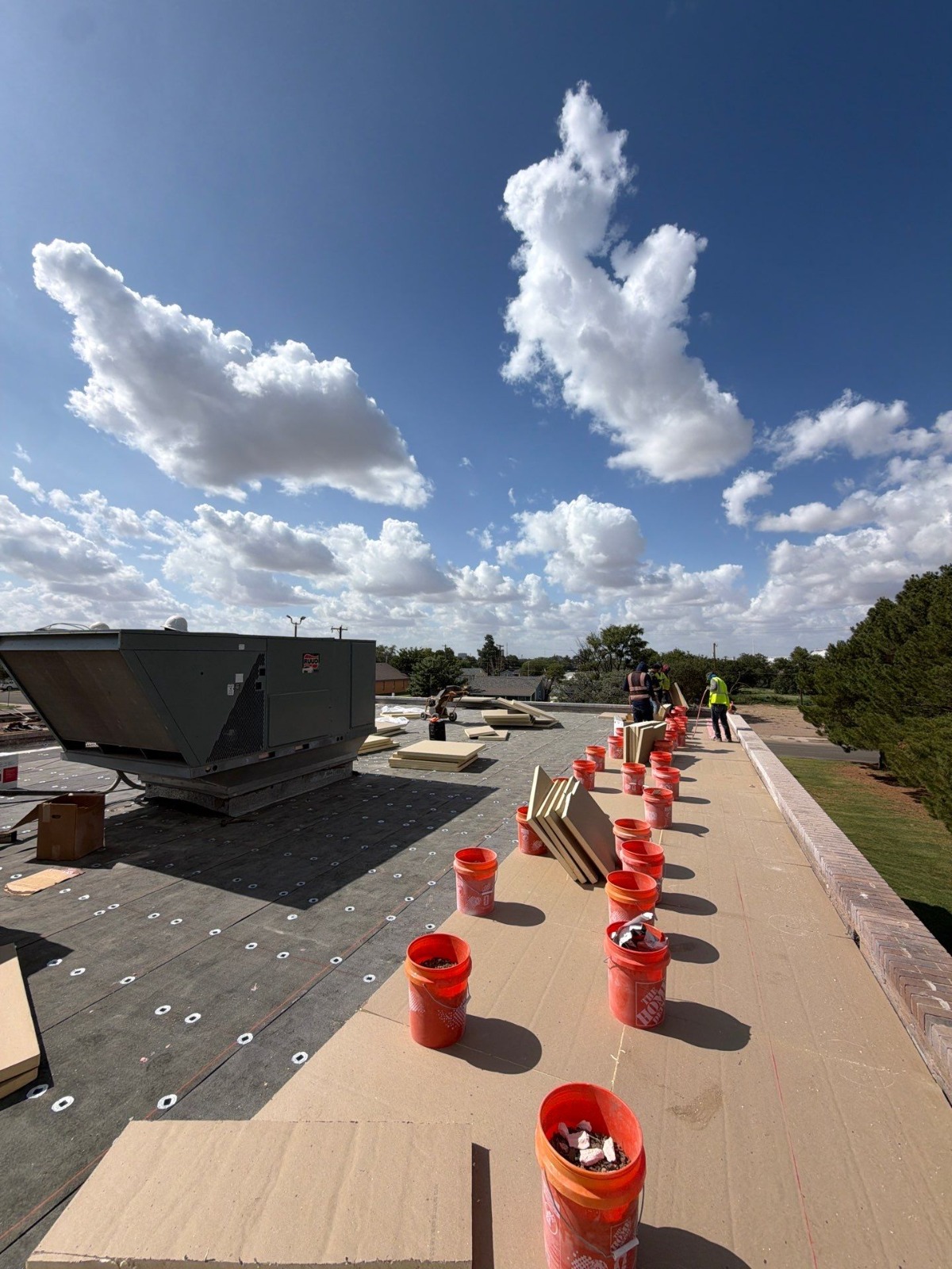 Polyiso insulation and cover board staged along the parapet during the senior center roof replacement