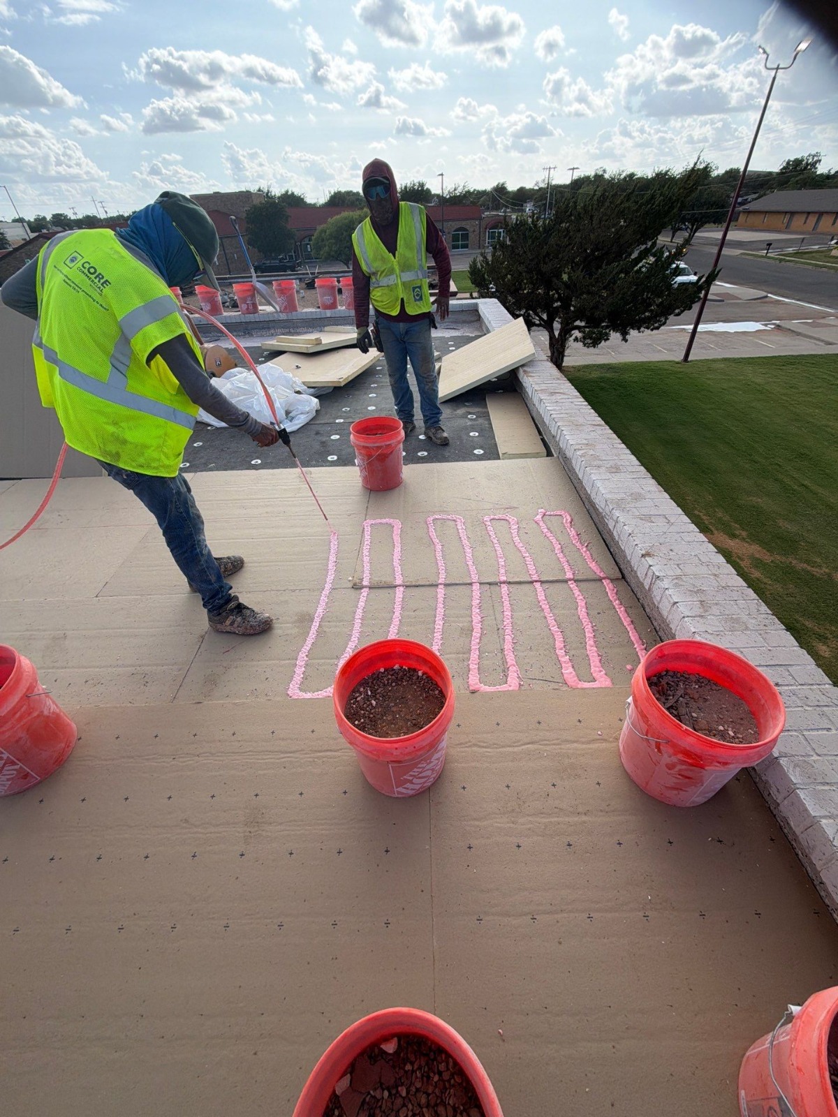 Crew applying ribbon adhesive on cover board before the fleeceback TPO membrane
