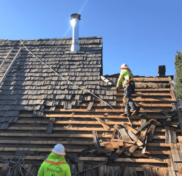 Roofing crew removing old wooden shingles during a commercial roof repair project in Texas.