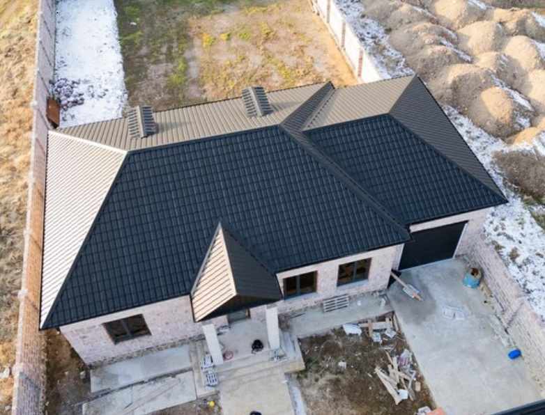 Aerial view of a modern house with a newly installed black metal roof, showing durable roofing design for long-lasting protection in Texas.