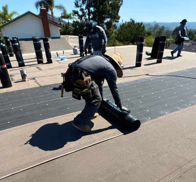 Roofing crew installing modified bitumen on a commercial flat roof for a durable, weather-resistant finish.