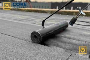 Professional application of rolled roofing material on a flat roof surface, illustrating installation techniques, by Core Commercial Roofing & Coatings.