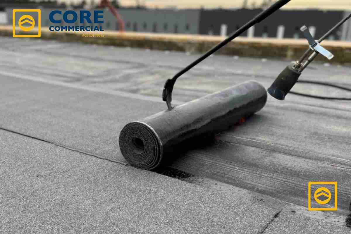 Professional application of rolled roofing material on a flat roof surface, illustrating installation techniques, by Core Commercial Roofing & Coatings.